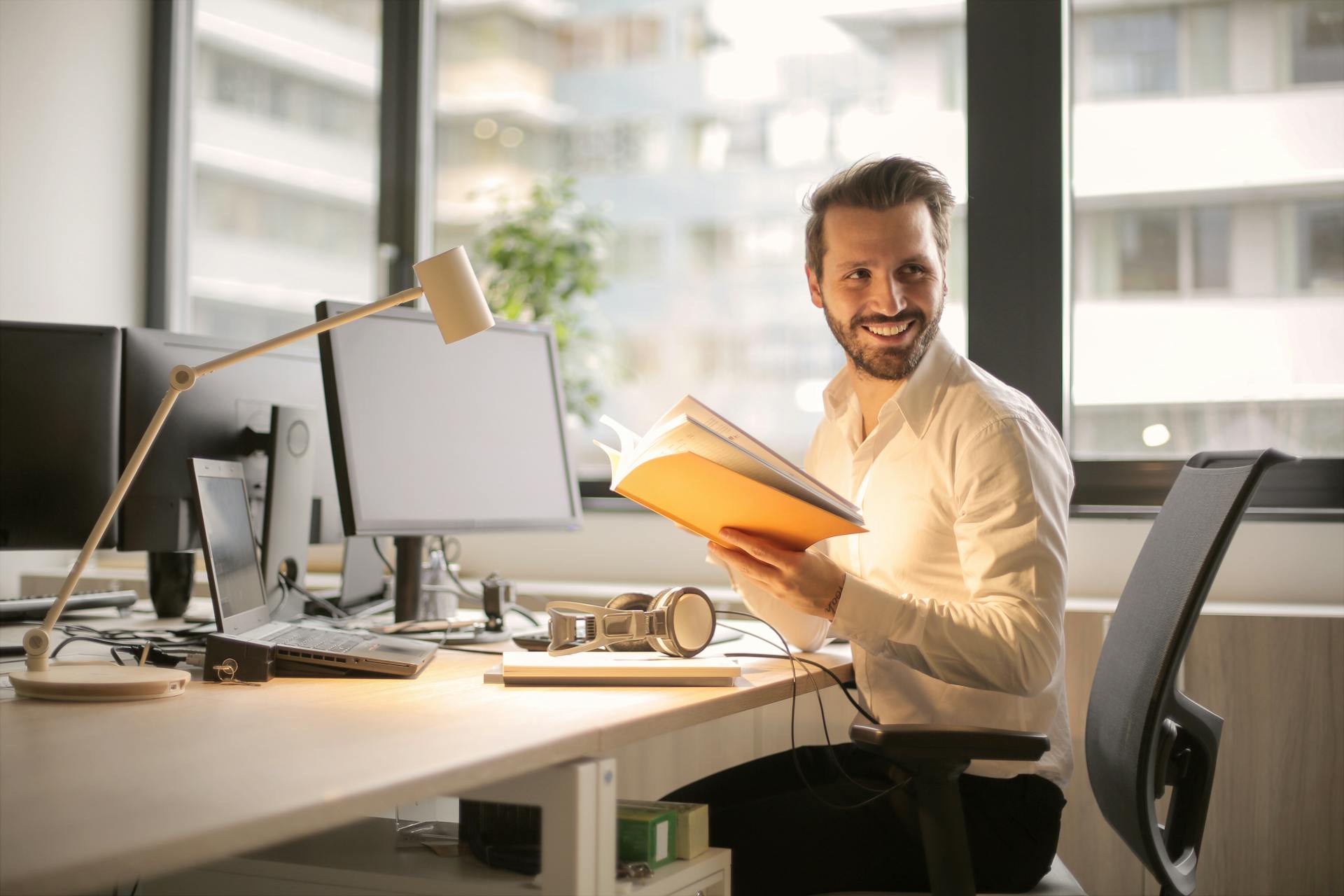 Smiling man holding a notebook in his office